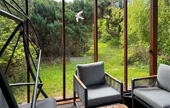 A modern outdoor seating area with metal frames and cushioned chairs, overlooking a lush garden. - Stunning home in Kalundborg with sauna (Kalundborg)