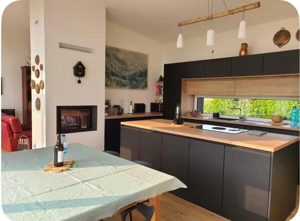 Eine moderne Küche mit dunklen Schränken, einer Holz Arbeitsplatte und einem großen Fenster.
