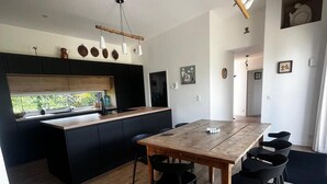 Eine moderne Küche mit einer zentralen Kochinsel, schwarzen Schränken und einem Holzespeisetisch mit Stühlen.