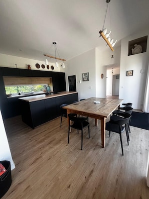 Eine moderne Küche mit einer zentralen Kochinsel, schwarzen Schränken und einem Holzespeisetisch mit Stühlen.