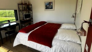 Ein Schlafzimmer mit einem Bett, einem Schreibtisch mit Computer, einem Fernseher und einem Bild an der Wand.