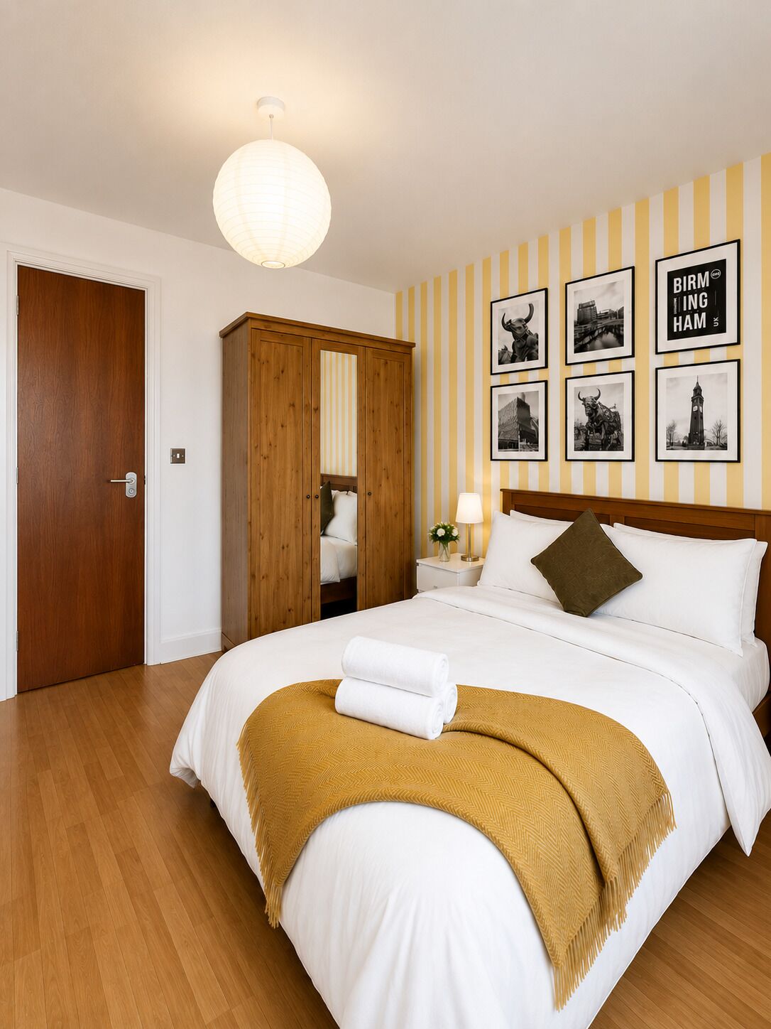 Een hotelkamer met een bed, een houten garderobe en een muur met zwart-witfoto's.