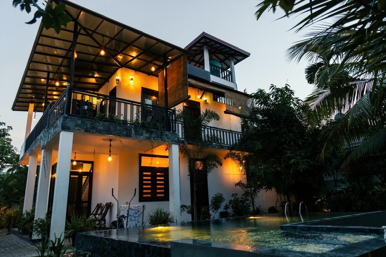 A two-story building with a balcony, a pool, and a well-lit entrance.