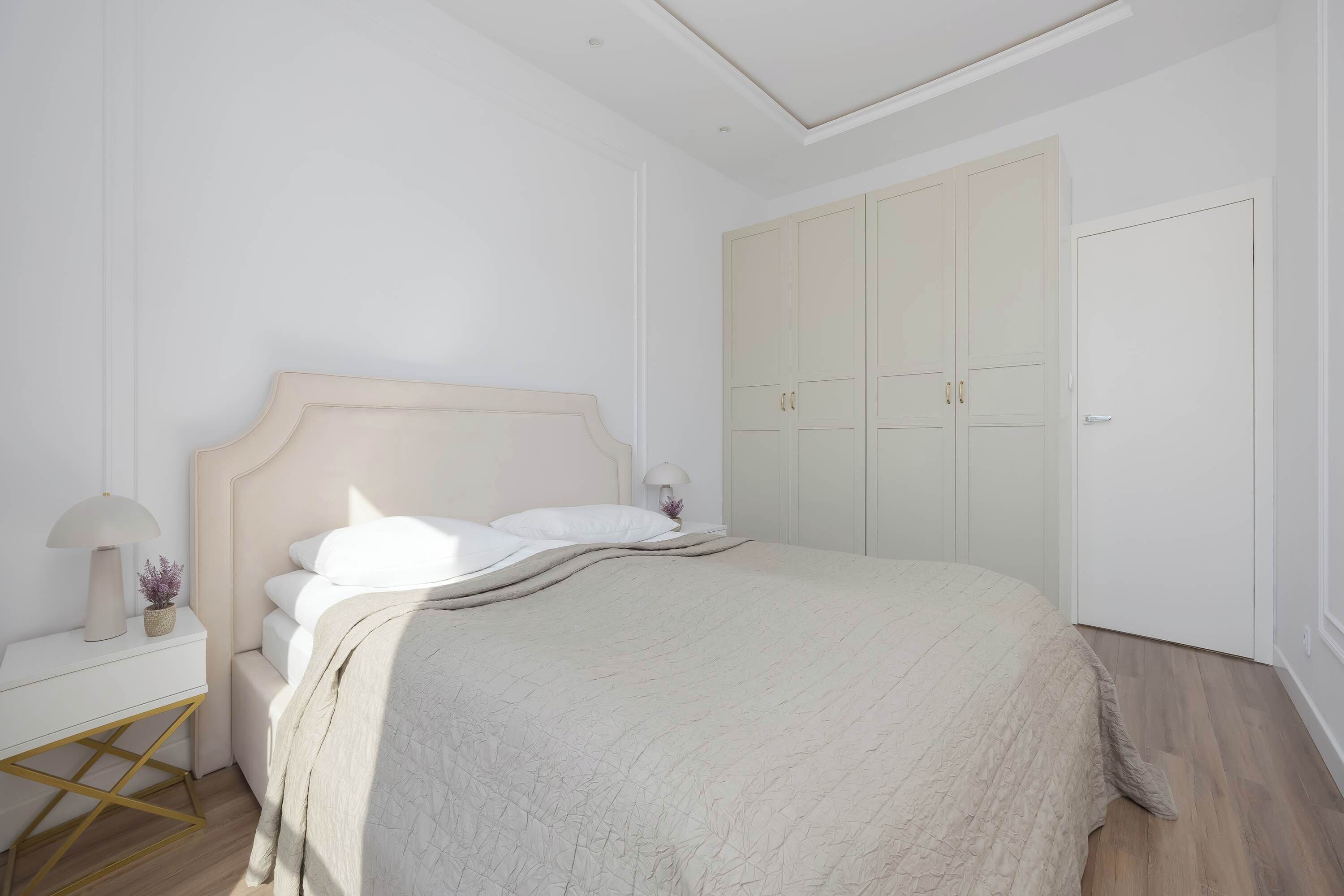 Une chambre à coucher avec un lit, une table de chevet, une lampe et une armoire.