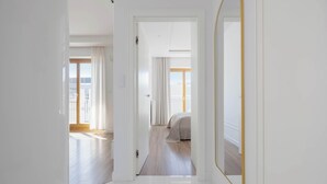 Ein Flur, der in ein Schlafzimmer mit großem Spiegel und Balkonblick führt.