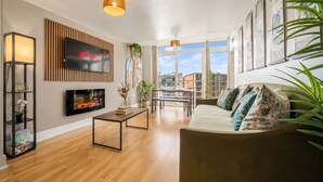Ein modernes Wohnzimmer mit Kamin, Flachbildfernseher und Essbereich mit Blick auf die Stadt.