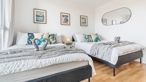 Ein Schlafzimmer mit zwei Betten, einem Nachttisch, einem Spiegel und gerahmten Kunstwerken an der Wand.