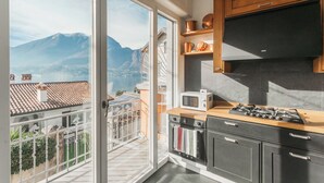 A kitchen with a view of mountains, a balcony, and a stove. - Villa Casa Pini (Bellagio)
