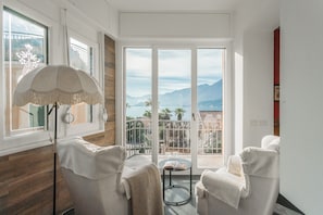 A room with a balcony, a large window, and a floor lamp. - Villa Casa Pini (Bellagio)
