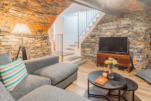 Una sala de estar con pared de piedra, un sofá, una mesa de centro con velas y un televisor.