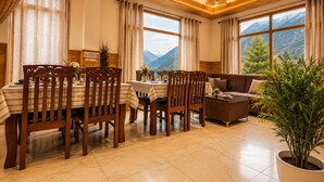 Un comedor con sillas de madera y una mesa, un sofá, y un ventanal con vistas a la montaña.