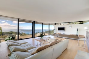 Ein modernes Wohnzimmer mit großem Fenster, Flachbildfernseher und einer Couch.