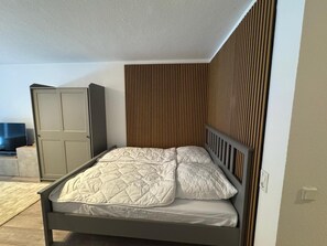 Une chambre à coucher avec un lit, une armoire et un téléviseur.