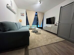 Ein Wohnzimmer mit einer Couch, einem Fernseher und einem Kleiderschrank.