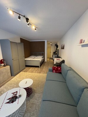 Um espaço compacto com cama, sofá e pequena área de refeições.