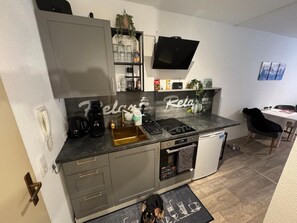 Une cuisine compacte équipée d’un four encastré, d’une machine à café et d’un évier.