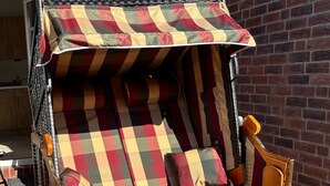 A wooden lounge chair with a checkered cushion, a matching canopy, and a small wooden table. - Apartment 'Meerestraum' with Wi-Fi (Norden)