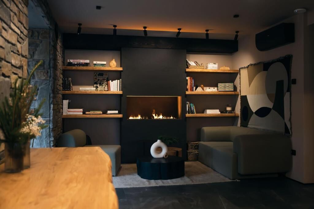 A modern living room with a fireplace, shelves with books and decorative items, a sofa, and a coffee table.