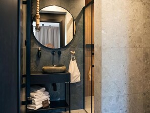 Une salle de bain moderne avec un miroir rond, un lavabo et un porte-serviettes.