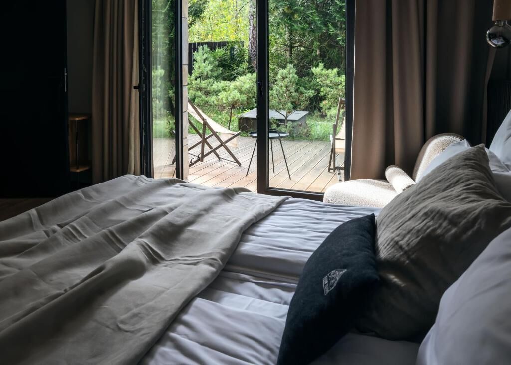 Un dormitorio con una ventana grande, una cama y vistas a una terraza exterior.