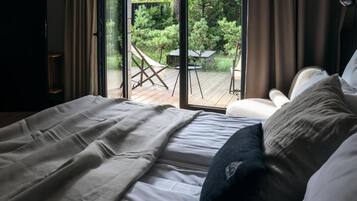 Un dormitorio con una ventana grande, una cama y vistas a una terraza exterior.