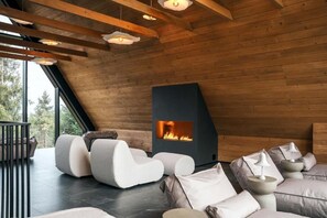 A modern interior with a fireplace, wooden ceiling beams, and contemporary seating.