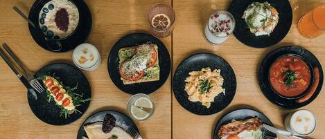 A table with various breakfast dishes, cutlery, and drinks.