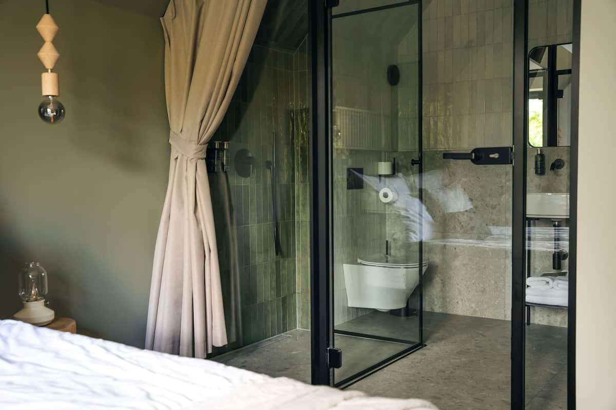 A modern bathroom with a glass shower enclosure, a toilet, and a sink.