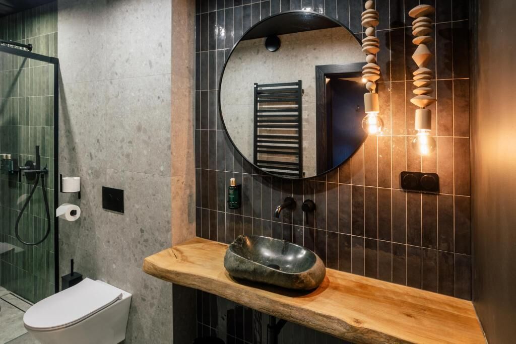 Un baño moderno con un espejo redondo, encimera de madera y lavabo integrado.