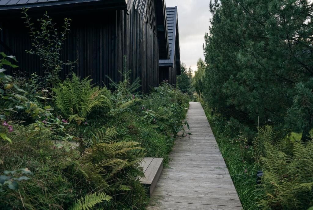 A wooden pathway leading to a modern building with vertical wooden panels.