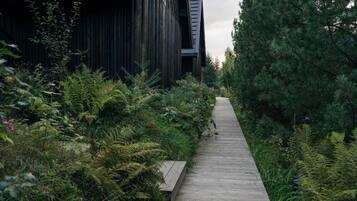 A wooden pathway leading to a modern building with vertical wooden panels.