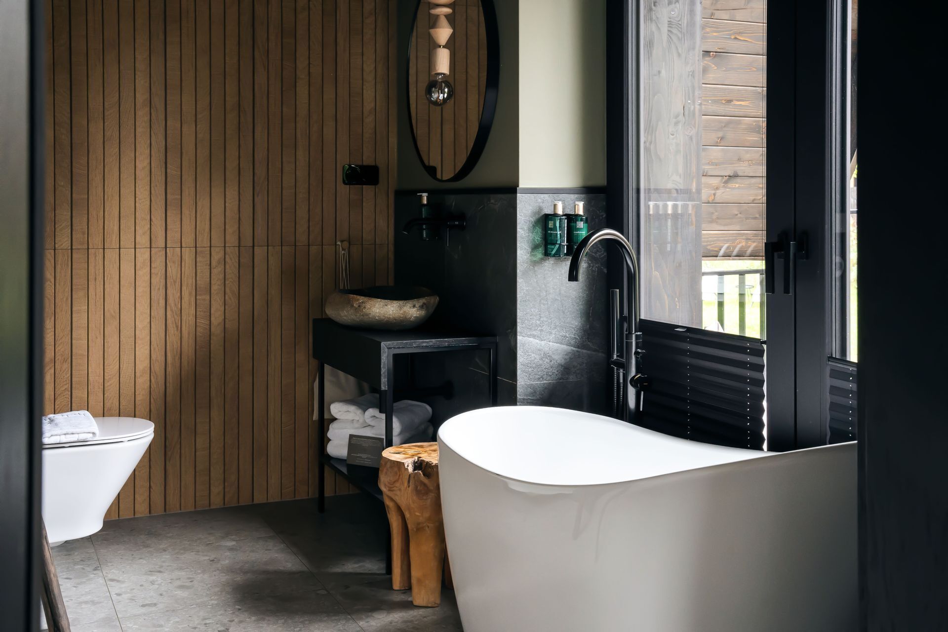 Une salle de bain moderne avec une baignoire sur pieds, un meuble-lavabo en bois, un lavabo rond et des toilettes.
