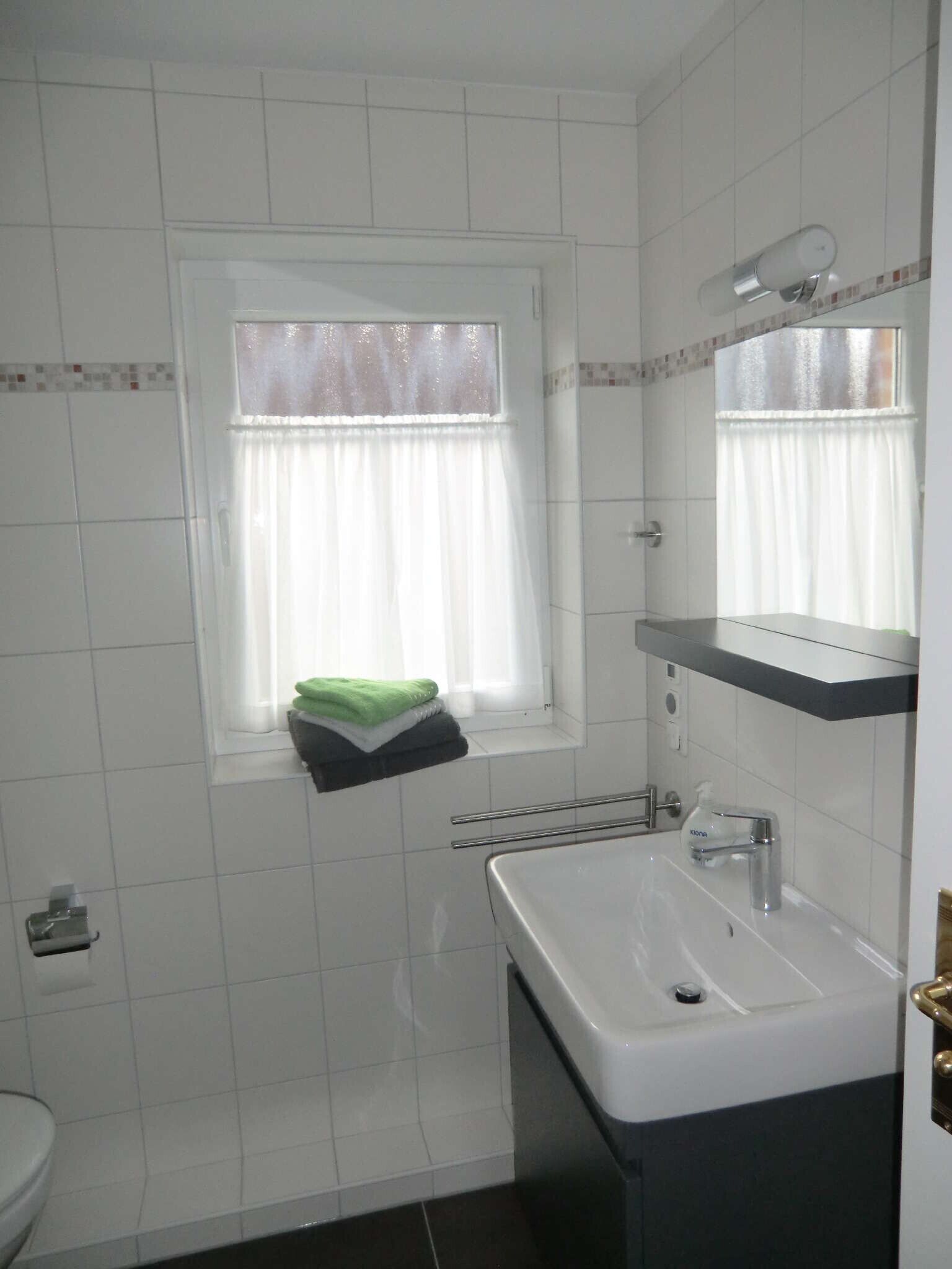 Une petite salle de bain avec une fenêtre, un lavabo et un porte-serviettes.