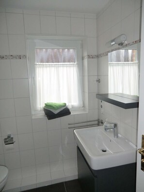 A small bathroom with a window, a sink, and a towel rack. - Frisiastrasse – Holiday Apartment Seestern (Norden)