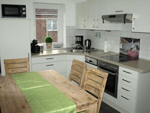 A compact kitchen with white cabinets, a microwave, a coffee maker, and a sink. - Frisiastrasse – Holiday Apartment Seestern (Norden)