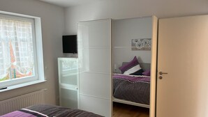 Ein Schlafzimmer mit Bett, Kleiderschrank und Fernseher an der Wand.