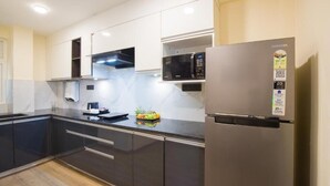 A modern kitchen with stainless steel appliances, a microwave, and a refrigerator. - Alaya Stays 1BHK Baljees Melville Utopia (Shimla)