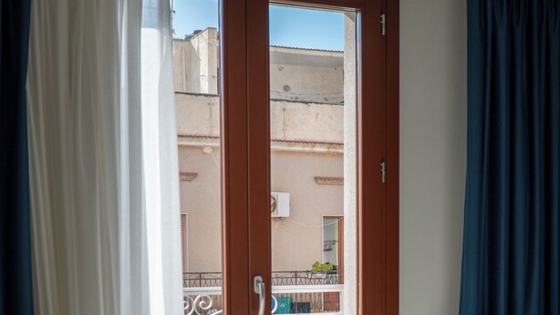 Een kamer met een bank, een houten deur en uitzicht op het balkon.