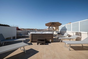 A rooftop terrace with a hot tub, lounge chairs, and a large umbrella. - Monnalisa Rooms (San Vito Lo Capo)