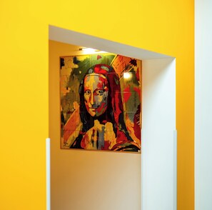 Una habitación con una pared amarilla y un cuadro abstracto grande.