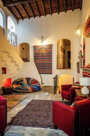 Ein gemütliches Interieur mit Treppe, einem farbenfrohen Teppich und einem roten Sofa.