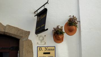 A wall with signs indicating 'D. Numo quartos - rooms' and a door with a stone archway.