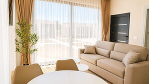 Un salon moderne avec un canapé beige, une table ronde et une plante en pot.