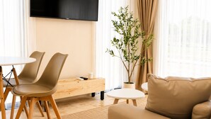 Un salon moderne comprenant un canapé, une table à manger avec des chaises, un téléviseur à écran plat fixé au mur et une plante en pot.
