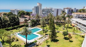 Ein Wohngebiet mit Swimmingpool, Palmen und Blick auf das Meer.