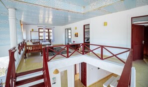 A multi-level interior with a staircase, wooden furniture, and a balcony.