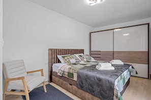A bedroom with a bed, a chair, and a wardrobe.