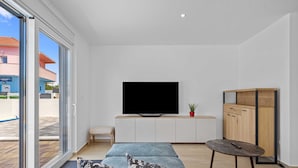 A modern living room with a sofa, a television, a small table, and a cabinet. - Villa Jurić (Vodice)