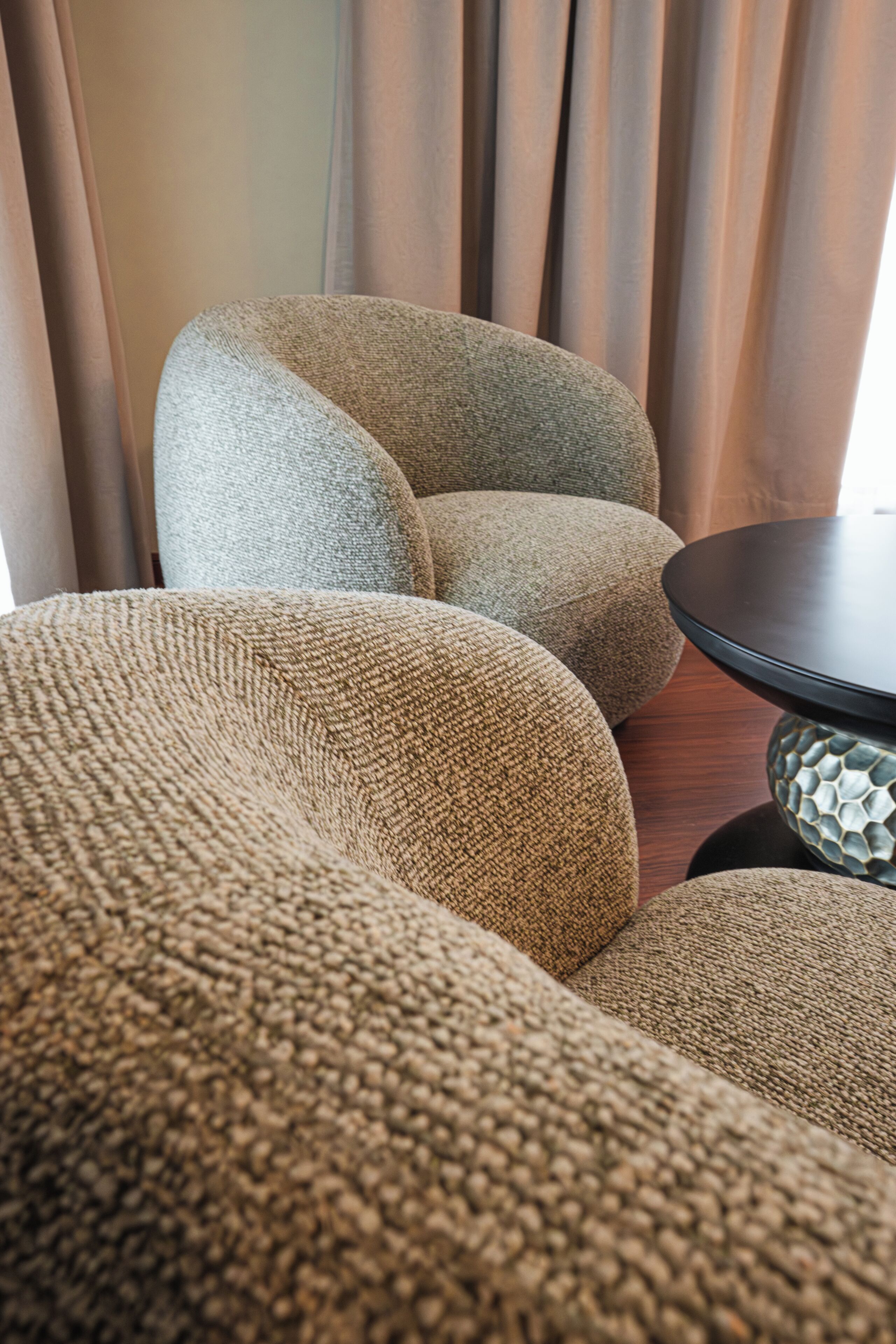A seating area with a round table and a textured sofa.