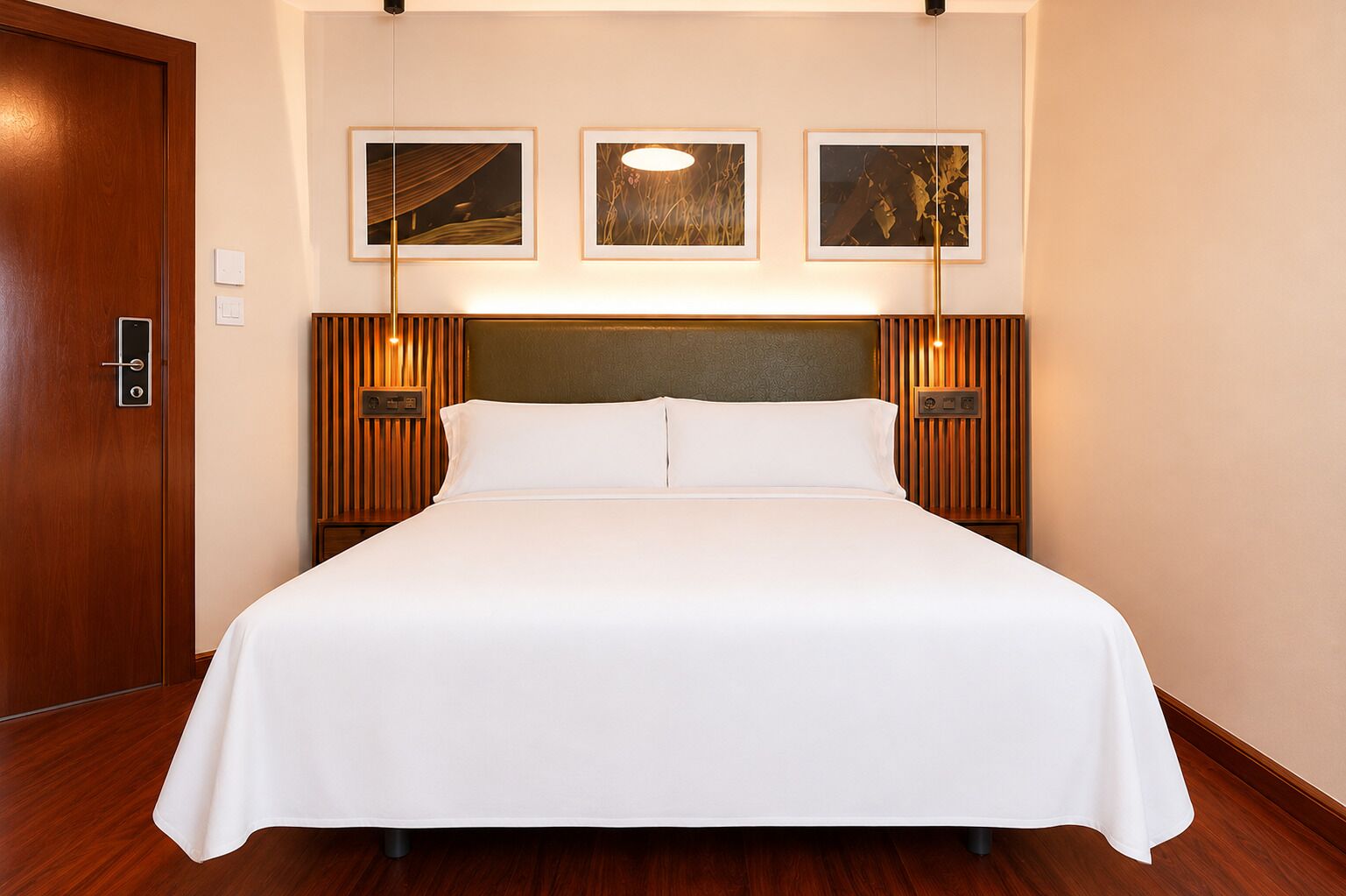 A neatly made bed in a hotel room with a wooden headboard, framed artwork on the wall, and a door with a handle.